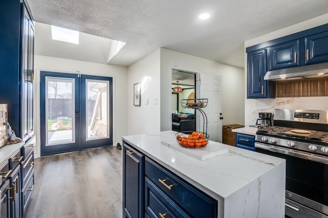 kitchen with blue cabinetry, stainless steel range with gas stovetop, a textured ceiling, a kitchen island, and dark hardwood / wood-style flooring