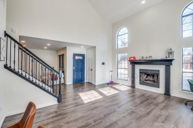 foyer with hardwood / wood-style floors, a high end fireplace, and high vaulted ceiling