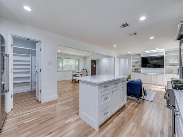 kitchen with white cabinetry, a center island, and light hardwood / wood-style floors