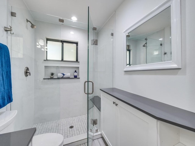 bathroom with walk in shower, vanity, and toilet