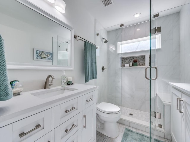 bathroom featuring vanity, a shower with door, and toilet