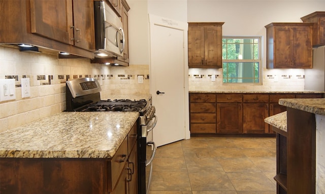 kitchen with light stone counters, backsplash, and stainless steel appliances