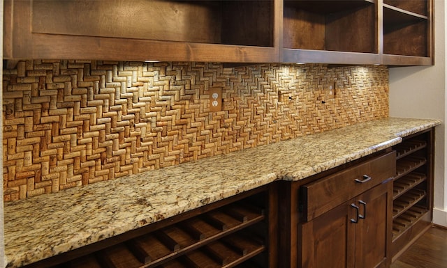 bar with tasteful backsplash, light stone countertops, and dark brown cabinets