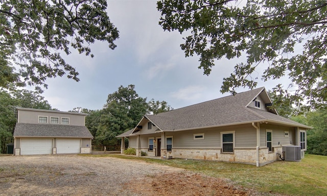 view of front of home with a garage, central AC unit, and a front lawn