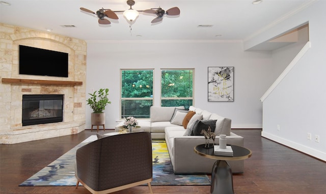 living room with ornamental molding, a stone fireplace, dark hardwood / wood-style floors, and ceiling fan