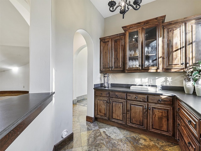 bar with dark brown cabinetry and an inviting chandelier