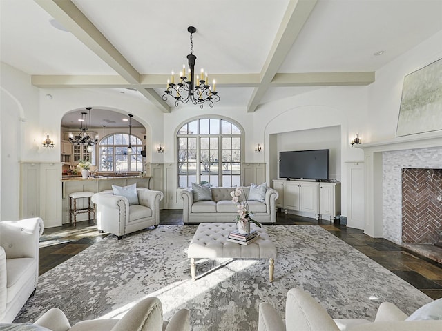 living room with beamed ceiling, a tiled fireplace, coffered ceiling, and a notable chandelier