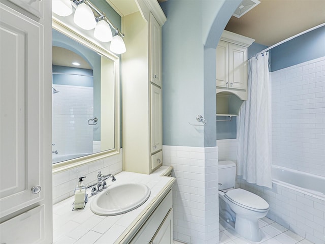 full bathroom featuring toilet, tile walls, vanity, shower / bathtub combination with curtain, and tile patterned flooring