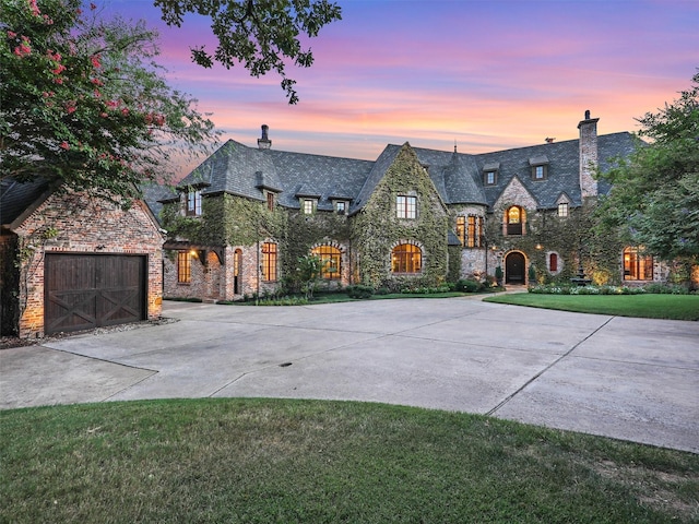 french country home featuring a garage and a yard