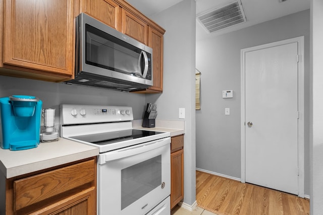 kitchen with electric range and light hardwood / wood-style flooring