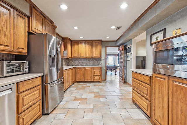 kitchen with tasteful backsplash, crown molding, and stainless steel appliances