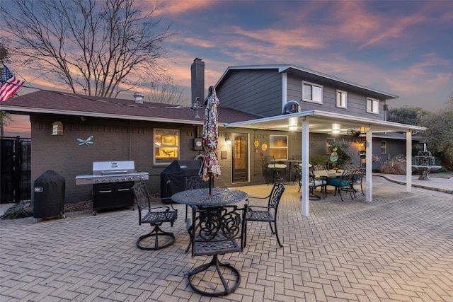 patio terrace at dusk featuring a grill