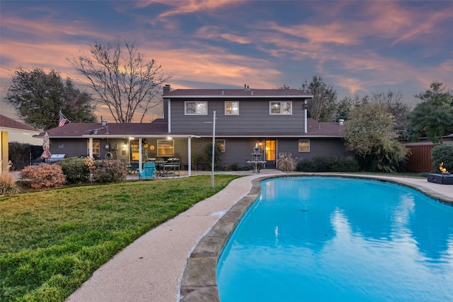 pool at dusk with a yard and a patio area