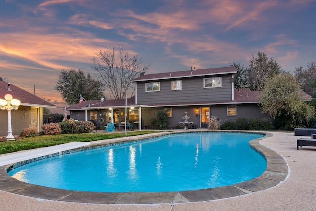 pool at dusk featuring a patio