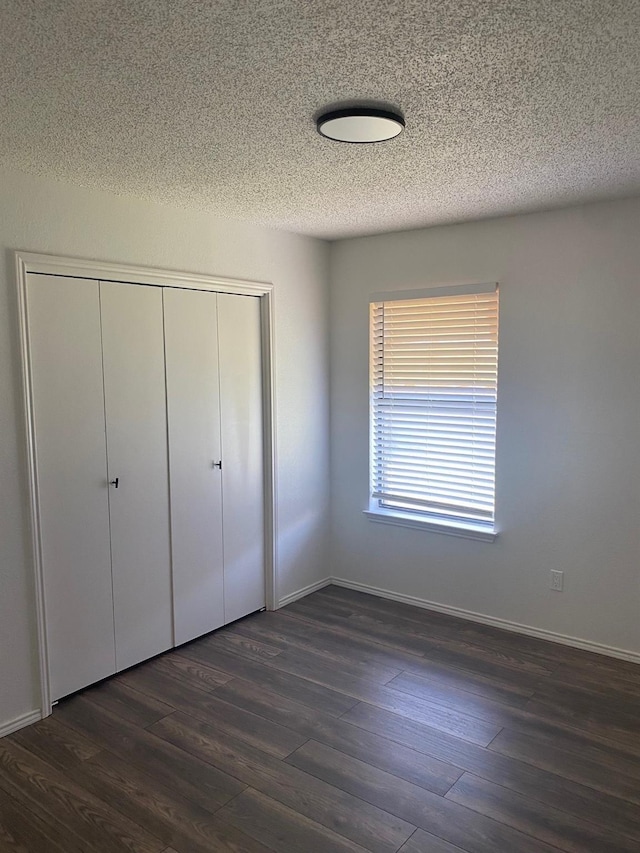 unfurnished bedroom featuring dark hardwood / wood-style flooring, a closet, and a textured ceiling