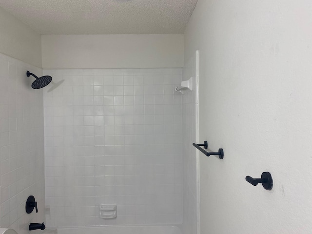 bathroom featuring tiled shower / bath and a textured ceiling