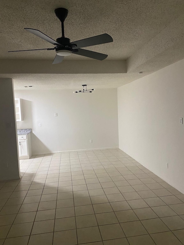 spare room with ceiling fan, a textured ceiling, and light tile patterned flooring