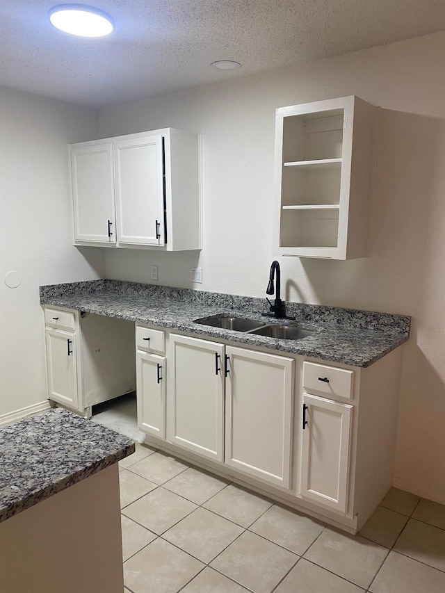 kitchen featuring sink, light tile patterned floors, a textured ceiling, and white cabinets