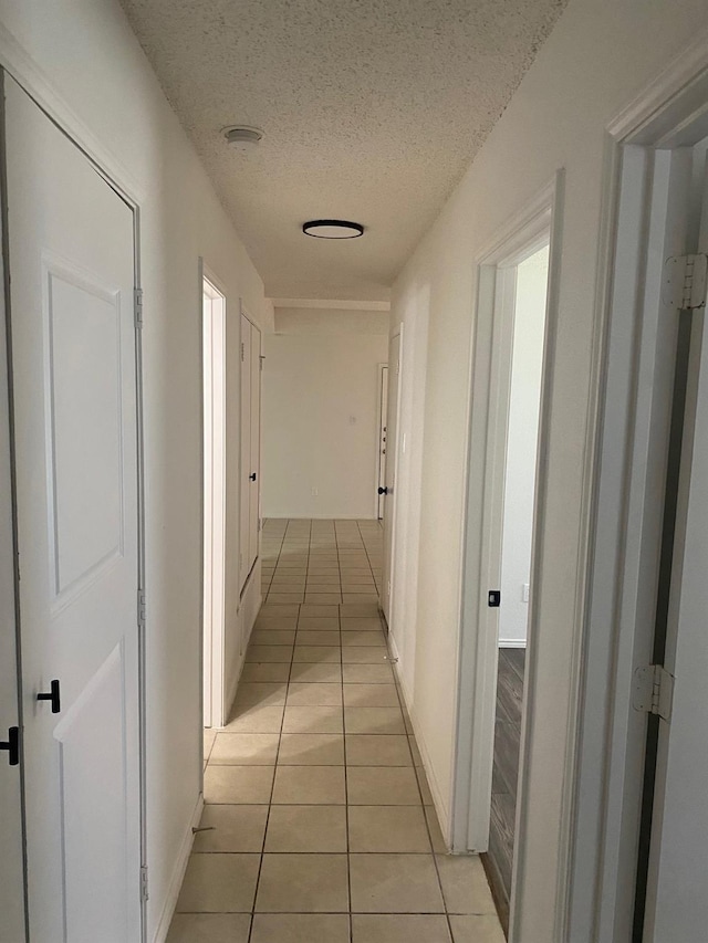 hall with light tile patterned floors and a textured ceiling