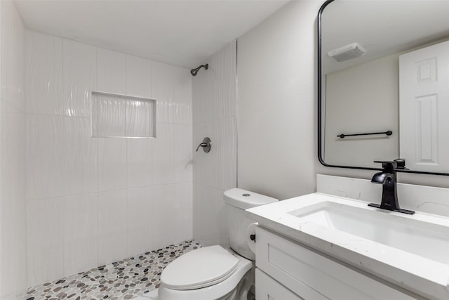 bathroom featuring vanity, toilet, and a tile shower