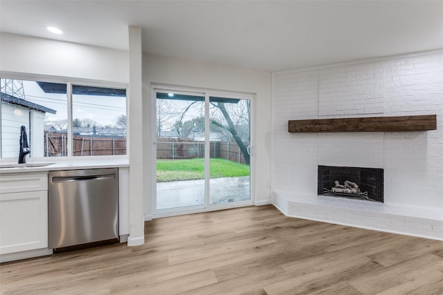 unfurnished living room with sink, a fireplace, and light hardwood / wood-style floors