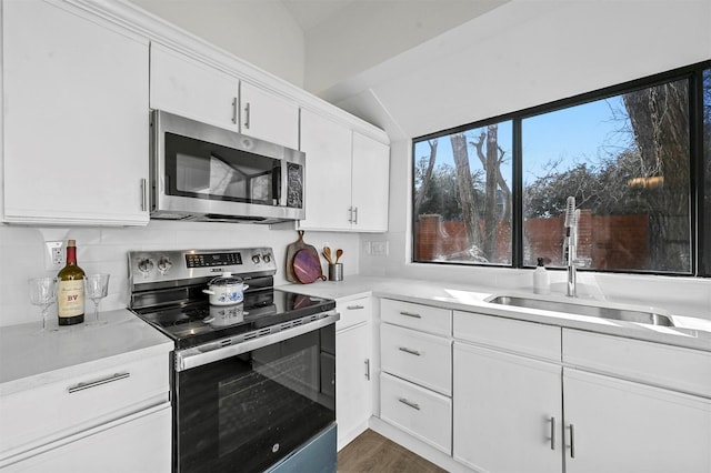 kitchen featuring appliances with stainless steel finishes, dark hardwood / wood-style floors, sink, white cabinets, and backsplash