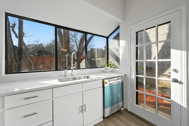 kitchen with dark wood-type flooring, stainless steel dishwasher, sink, and white cabinets