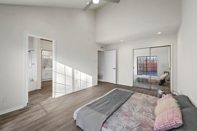 bedroom featuring dark wood-type flooring, a towering ceiling, ceiling fan, and a closet