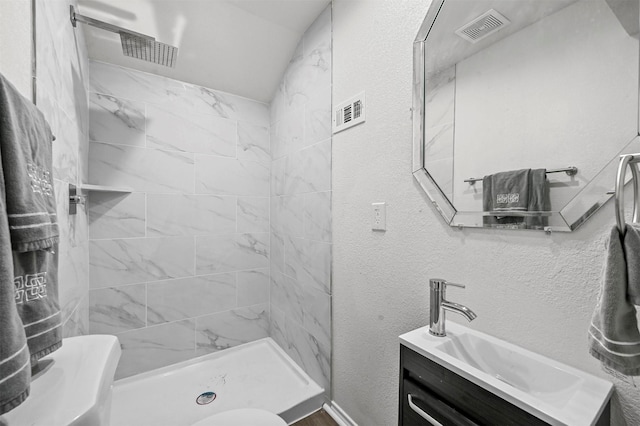 bathroom featuring vanity, toilet, and a tile shower