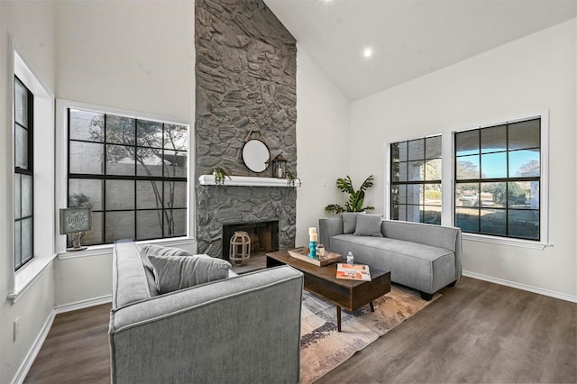 living room featuring dark wood-type flooring, a stone fireplace, and high vaulted ceiling