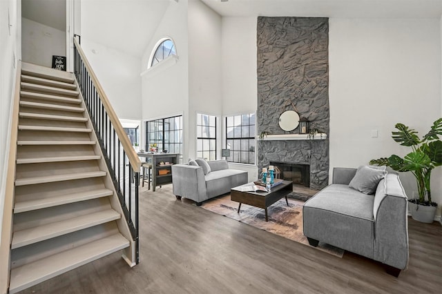 living room with dark wood-type flooring, a fireplace, and a towering ceiling