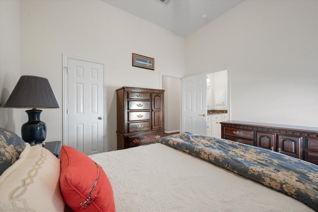 bedroom featuring high vaulted ceiling and ensuite bathroom