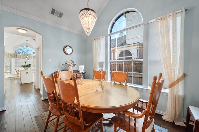 dining space with an inviting chandelier, crown molding, and dark wood-type flooring