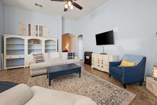 living room with ceiling fan and a towering ceiling