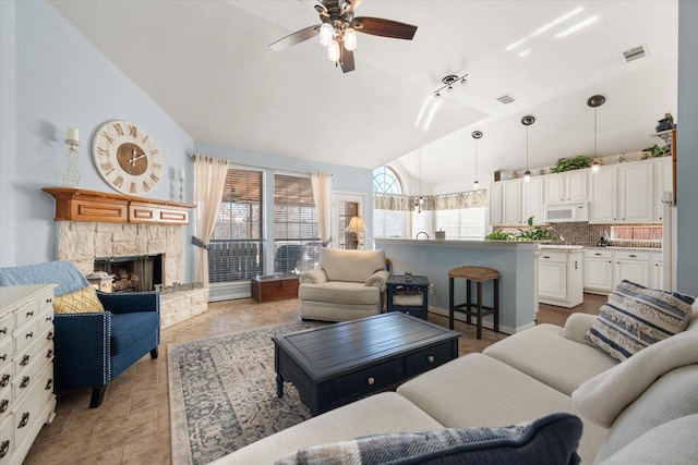 living room with ceiling fan, a fireplace, and vaulted ceiling