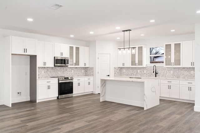 kitchen with white cabinetry, stainless steel appliances, a center island, and hanging light fixtures