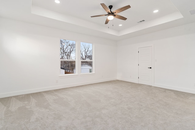 unfurnished room featuring light carpet, ceiling fan, and a tray ceiling