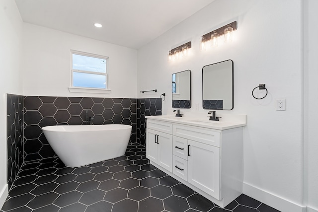 bathroom with a washtub, vanity, tile patterned flooring, and tile walls