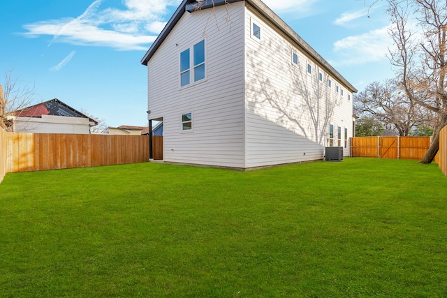 back of house with central AC and a lawn