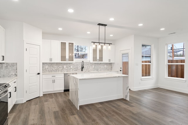 kitchen with a kitchen island, appliances with stainless steel finishes, white cabinets, hanging light fixtures, and light stone counters