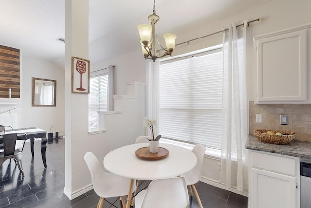 dining space with lofted ceiling, dark tile patterned floors, and a chandelier