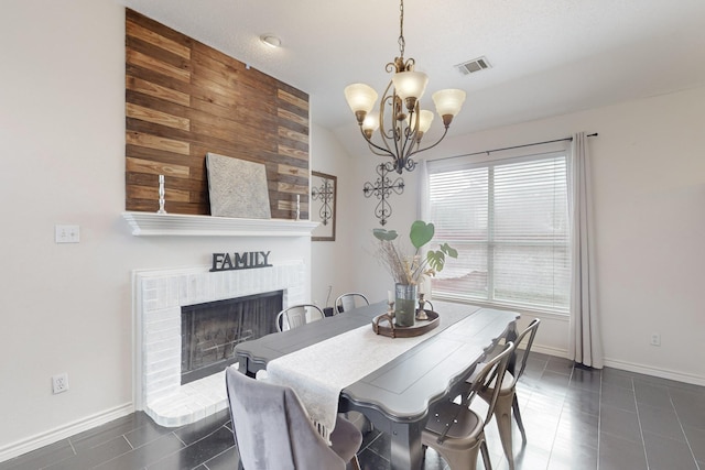 dining room featuring dark tile patterned floors, vaulted ceiling, a notable chandelier, and a fireplace