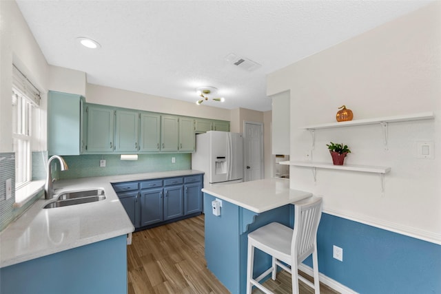 kitchen with sink, dark wood-type flooring, a breakfast bar, tasteful backsplash, and white refrigerator with ice dispenser