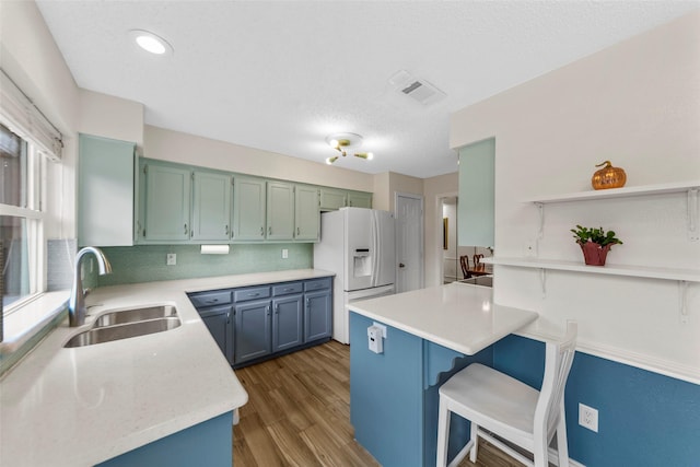 kitchen featuring sink, dark hardwood / wood-style floors, white refrigerator with ice dispenser, decorative backsplash, and kitchen peninsula