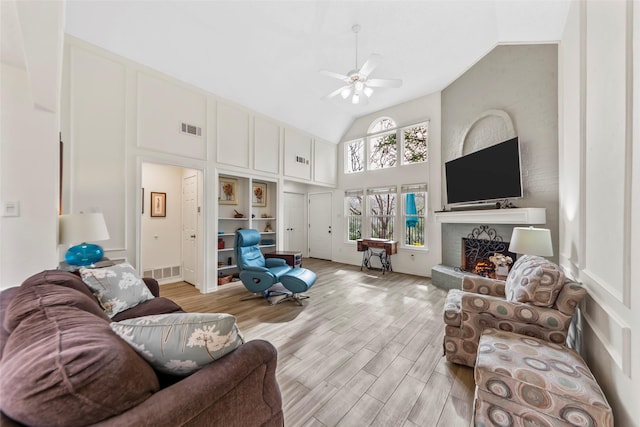 living room featuring light hardwood / wood-style flooring, high vaulted ceiling, and ceiling fan