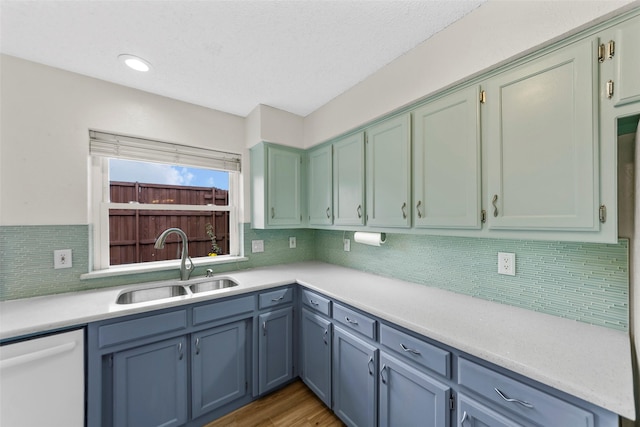 kitchen with tasteful backsplash, sink, dark wood-type flooring, and dishwasher