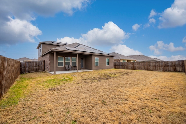 rear view of house featuring a yard, a patio, and solar panels