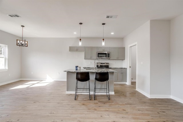 2604 Creekview Dr, Granbury, TX 76048 - kitchen with stainless steel appliances, gray cabinets, light wood-style floors, decorative backsplash, and recessed lighting