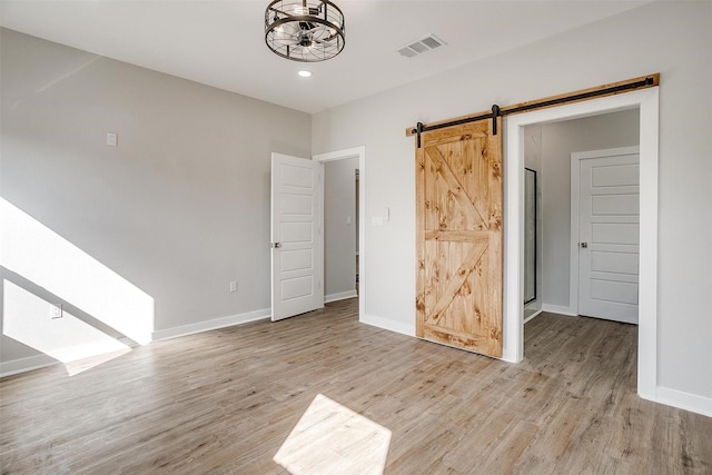 empty room featuring a barn door and light hardwood / wood-style floors