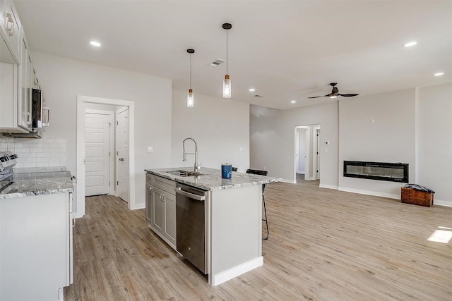 2604 Creekview Dr, Granbury, TX 76048 - kitchen with appliances with stainless steel finishes, a sink, light wood finished floors, a ceiling fan, and an island with sink
